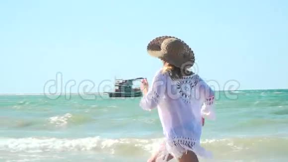 带着帽子和白色长袍的年轻金发女子在泰国海滩上活动视频的预览图