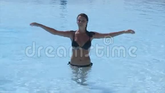 布鲁内特年轻的女孩在游泳池里把所有的夏日阳光明媚假日飞溅视频的预览图