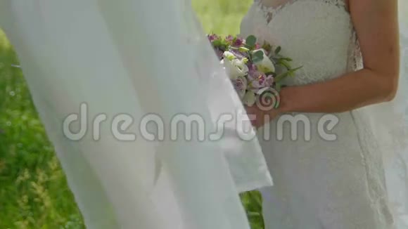 新娘在草地户外慢动作地捧着她的婚礼花束视频的预览图