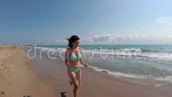 镜头移向女子身后慢动作地沿着海边奔跑视频的预览图