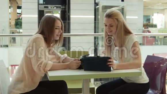 两个在娱乐中心的女孩在平板电脑里说话和看视频的预览图