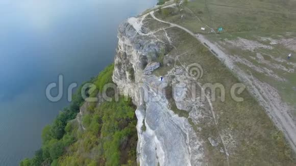 群山之间的湖上日落很大一对夫妇在悬崖边拥抱4k空中飞行视频的预览图
