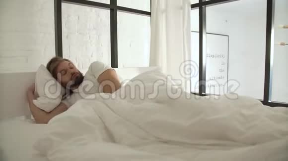 男人睡觉早上醒来躺在床上穿着白色亚麻布视频的预览图