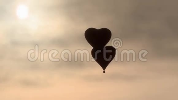 两个气球心形飞行在黎明的阴霾中视频的预览图