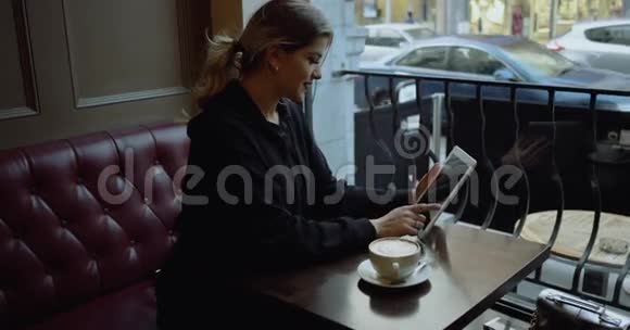 咖啡馆里有平板电脑的快乐年轻女人4k视频的预览图