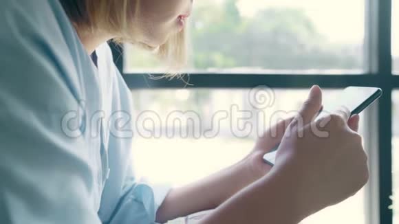 商务自由职业亚洲妇女使用智能手机交谈阅读和短信而坐在桌子上的咖啡馆视频的预览图