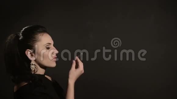 美丽的女人在黑色背景上抽烟视频的预览图