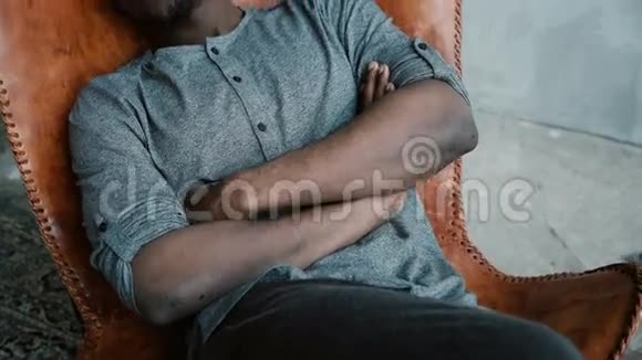 长着胡子的英俊的非洲男人坐在椅子上微笑一个男的看起来很梦幻很体贴很冷静视频的预览图