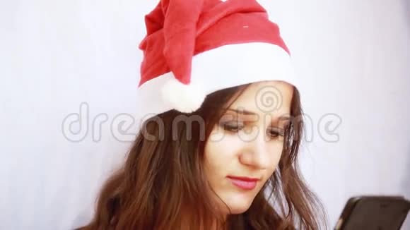 戴着圣诞老人帽子的漂亮年轻女人用手机1920x1080视频的预览图