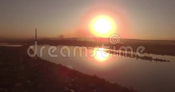 空中观景日落在湖面上海岸上有一个小城市工业工厂在地平线上4K视频的预览图