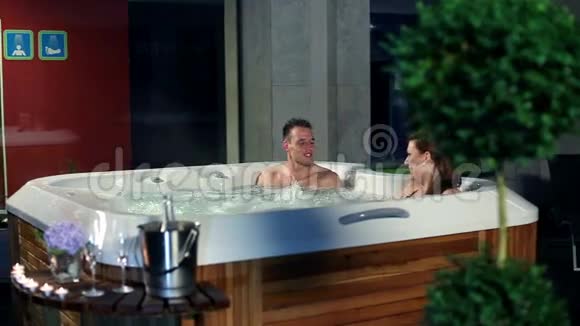 年轻夫妇在按摩浴缸里放松前面有糖果视频的预览图