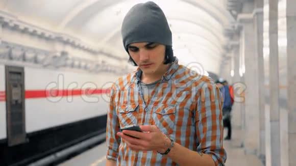年轻的白种人在地铁站台上用手机说话视频的预览图