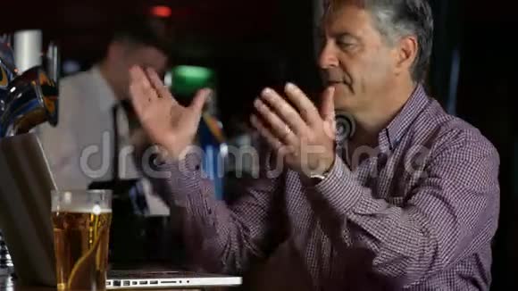 沮丧的男人在酒吧里用笔记本电脑喝一品脱视频的预览图