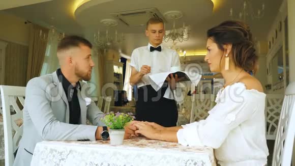 服务员在咖啡馆里给美女夫妇端来一杯咖啡视频的预览图