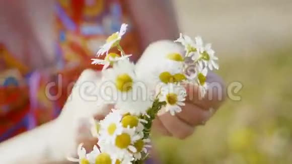 穿着红衣服的女人在花丛中收集一个雏菊花圈非常靠近视频的预览图