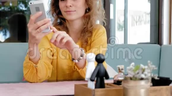 在咖啡馆里使用智能手机触摸屏的女人视频的预览图