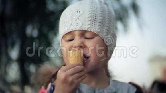 穿白色针织帽子的可爱学步女孩吃冰淇淋视频的预览图