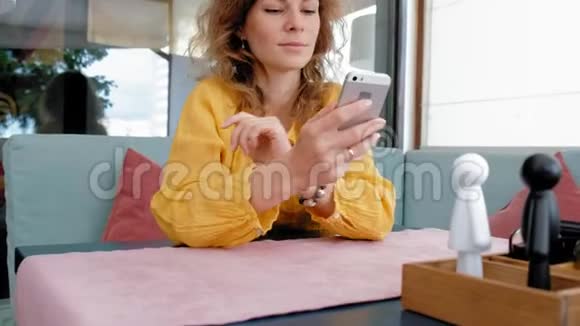 在咖啡馆里使用智能手机触摸屏的女人视频的预览图