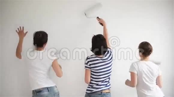 朋友在家修理有趣的女孩跳舞在公寓里粉刷墙壁视频的预览图