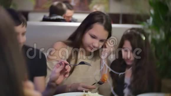 十几岁的女孩和朋友在咖啡馆里吃肉沙拉在智能手机上听音乐一群人快速地视频的预览图