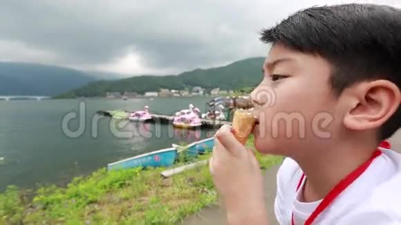 年轻的亚洲男孩吃冰淇淋湖畔景色视频的预览图
