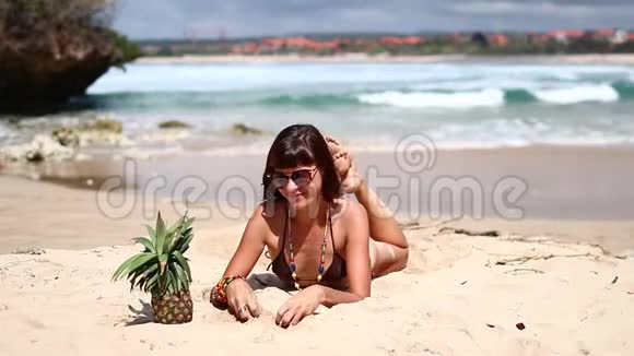 穿着棕色泳衣的女人和菠萝在海滩上在热带巴厘岛享受暑假的年轻女性视频的预览图
