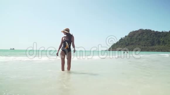 年轻女子沿着海边沙滩散步视频的预览图