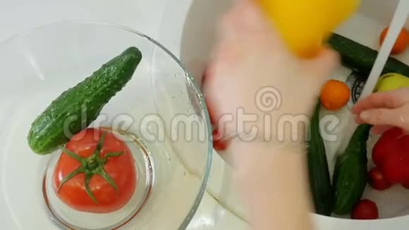 女人在厨房的水槽里的水龙头下面洗新鲜蔬菜把它们放进玻璃杯里视频的预览图