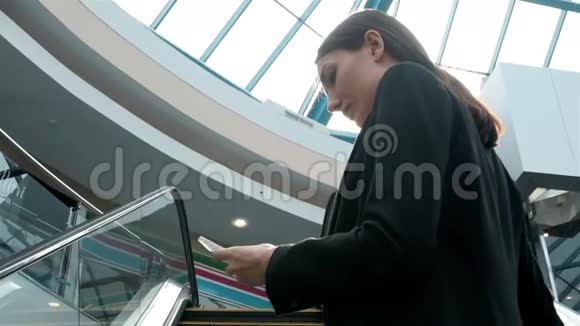 年轻的女商人肖像在自动扶梯上的电话交谈在商场或办公室工作的女商人视频的预览图