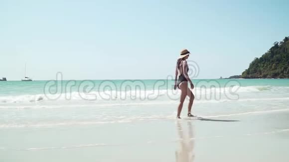 年轻女子沿着海边沙滩散步视频的预览图