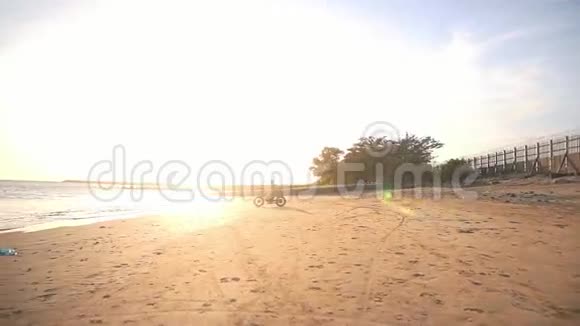 日落时骑摩托车的人在海滩上驾驶摩托车视频的预览图