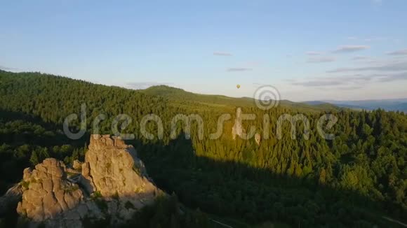 热空气气球在岩石附近的山脉中飞过天空视频的预览图