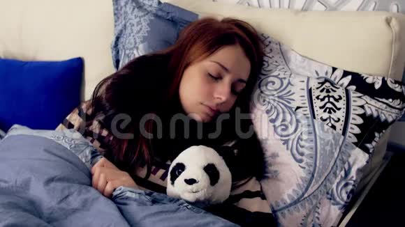 生病的年轻女人和熊猫玩具睡在床上视频的预览图