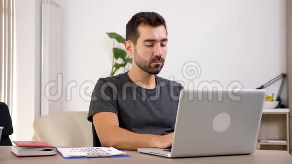 男人在客厅的笔记本上打字视频的预览图
