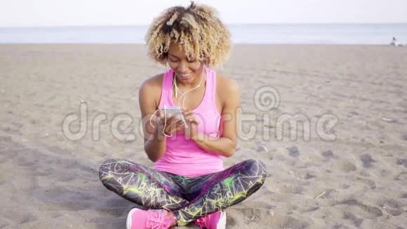 时髦的年轻女子在海滩上听音乐视频的预览图