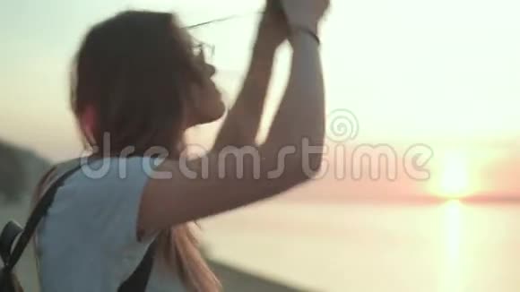 美丽的女人在海边的溜冰鞋里听音乐视频的预览图