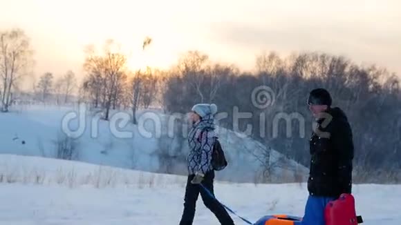 一家人用雪管上升到雪山慢动作冬天的雪景日落时间视频的预览图