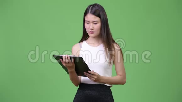 年轻漂亮的亚洲女商人拿着剪贴板思考视频的预览图