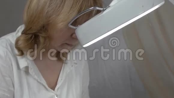 美容师看着放大镜把凝胶放在美容院女人的眼睛下面视频的预览图