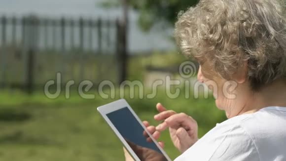 老年妇女在户外手持电脑平板电脑视频的预览图