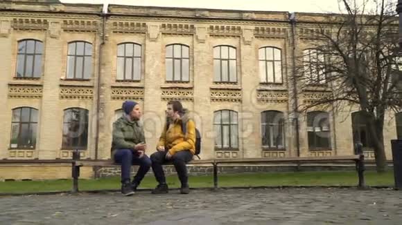 两个学生坐在校园附近的长凳上视频的预览图