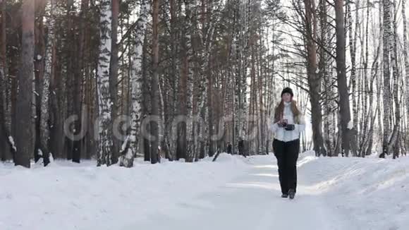 快乐微笑的女人冬天在森林里喝杯热咖啡或茶视频的预览图