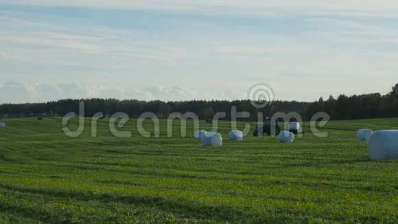 拖拉机在田间收集干干草后裹上一捆干草视频的预览图
