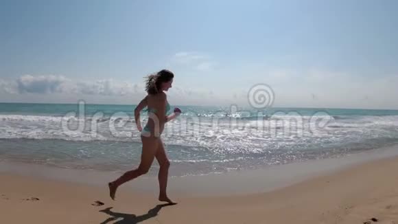 镜头移向女子身后慢动作地沿着海边奔跑视频的预览图