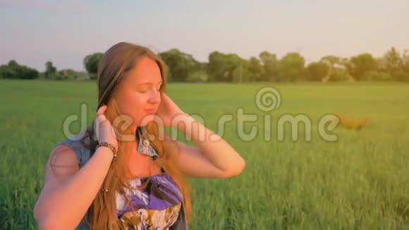 夕阳下一头直发的小女孩走在一片绿色的田野上平均射击在大自然中放松慢动作视频的预览图