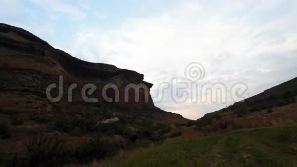 在南非雄伟的金门高地国家公园的岩石悬崖上日落时移动的云视频的预览图
