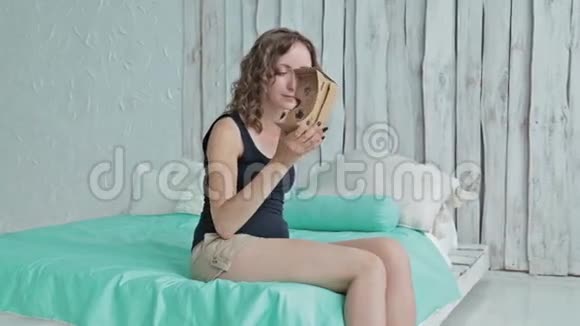 年轻女子使用虚拟现实眼镜坐在床上多利射击视频的预览图