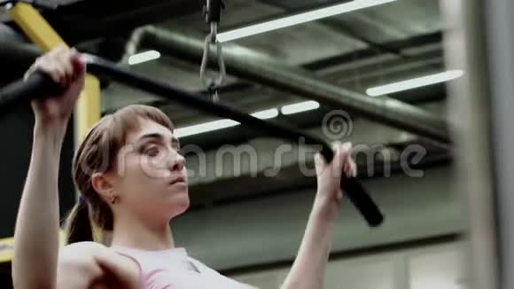 美丽苗条的年轻女性健身模型训练背部和手臂肌肉视频的预览图