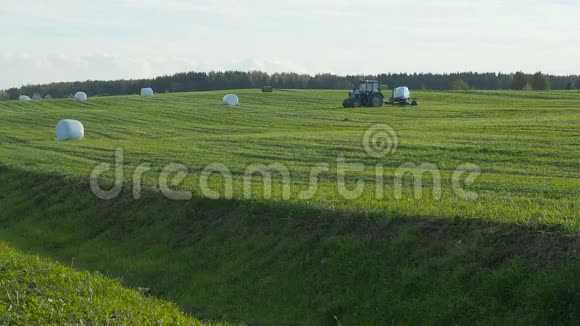 拖拉机在田间收集干干草后裹上一捆干草视频的预览图