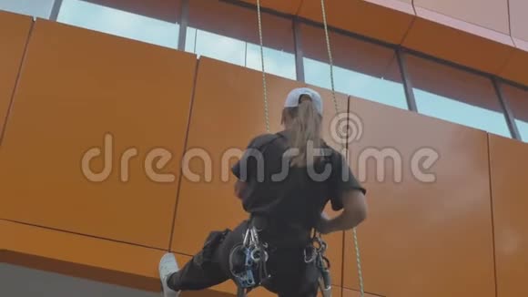 女子跳高运动员在建筑物上的专业设备上爬下来视频的预览图